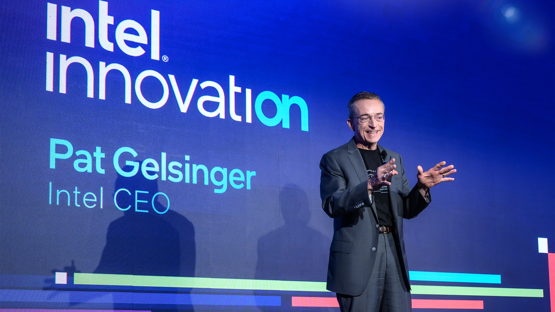 A person in a suit is speaking on stage at an event. The background displays the text intel innovation and Pat Gelsinger, Intel CEO. Colorful lines are visible beneath the text.