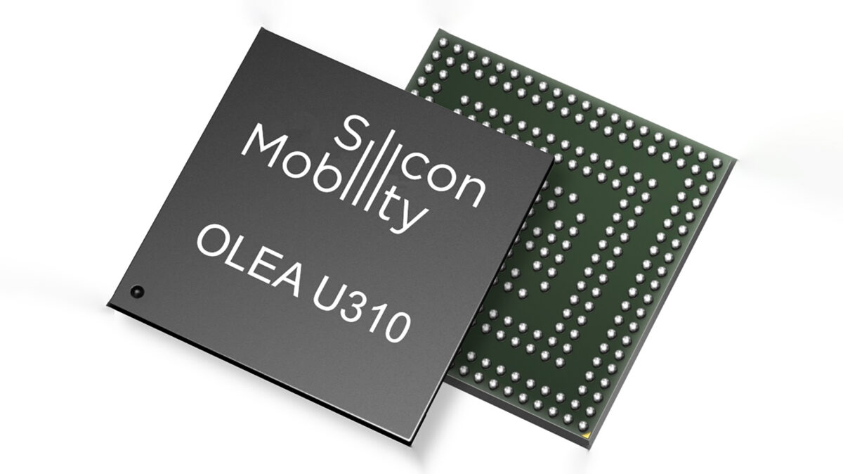 Close-up of two microchips, one black labeled Silicon Mobility OLEA U310 with white text, and another green one featuring numerous metal contacts on its surface. The image is on a white background, showcasing the design and detailing of the chips.