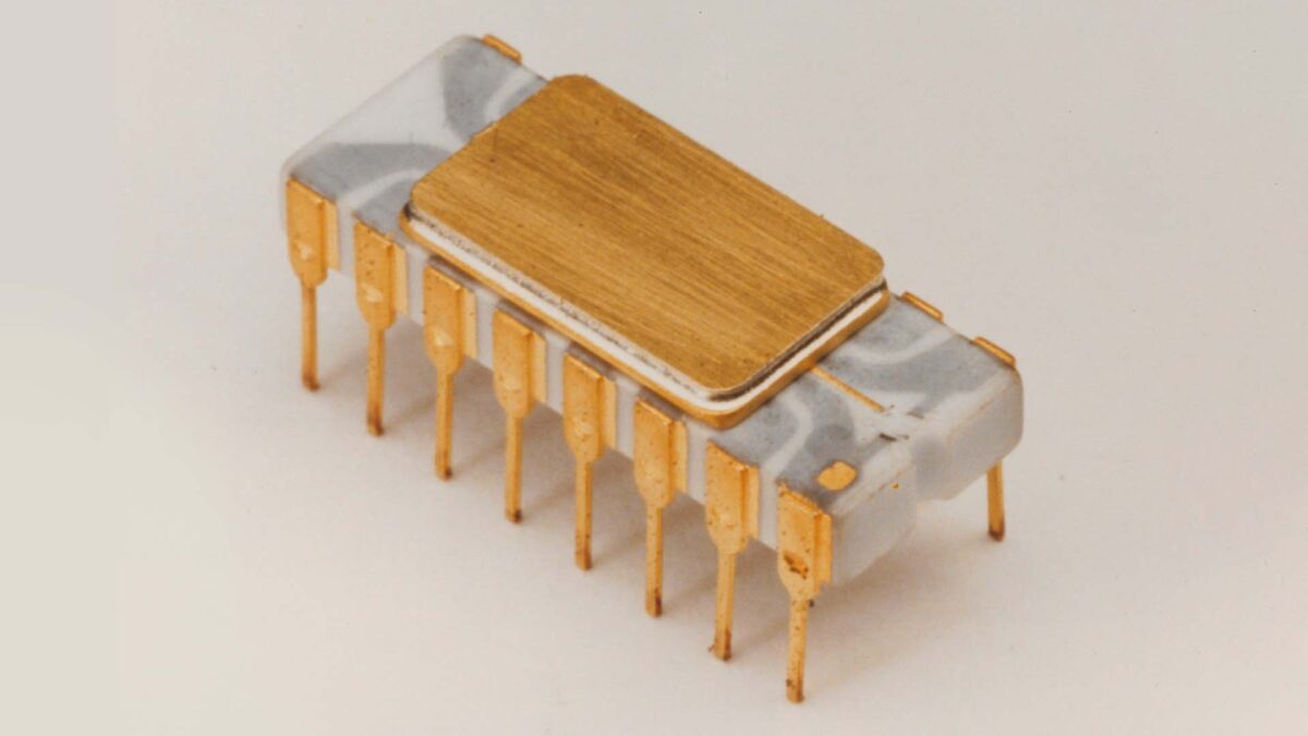 A vintage integrated circuit chip with a ceramic and metal body features multiple metal pins for connectors, displayed against a plain background.