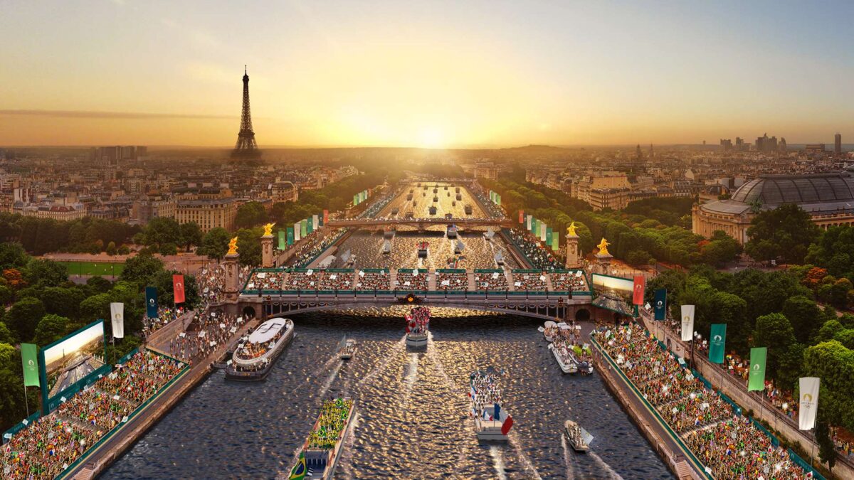 A scenic view of the Eiffel Tower at sunset with a parade of boats on the Seine River. The riverbanks are lined with spectators and vibrant banners, and lush greenery surrounds the scene, capturing the essence of a lively celebration.