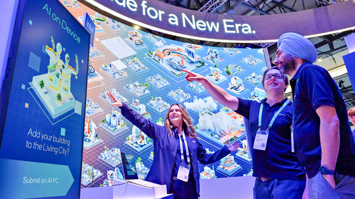 Three people are engaged with a large, colorful digital display about AI technology. Two point at the screen while another stands nearby. The backdrop shows futuristic city elements, and a sign reads, AI on Device for a New Era.