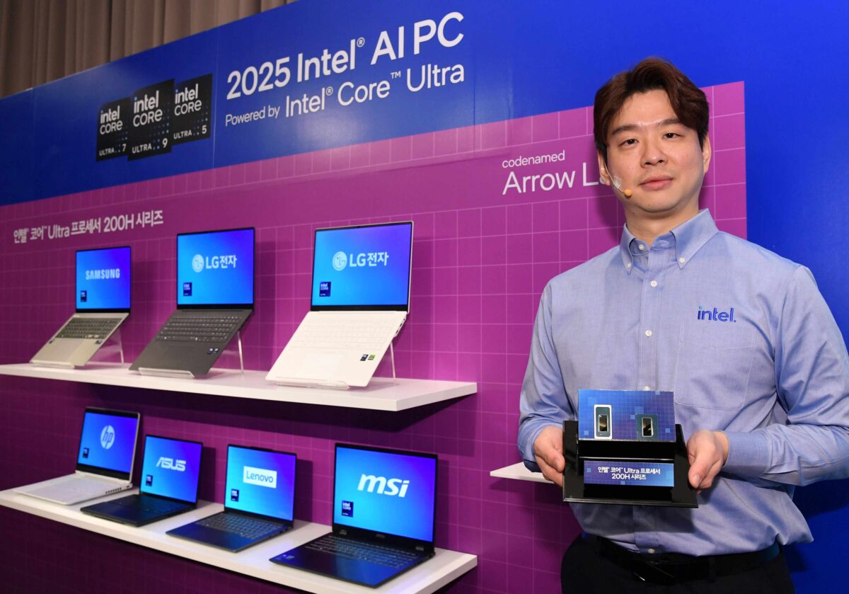 A person stands holding a box in front of a display featuring various laptops from brands like Samsung, LG, ASUS, Lenovo, and MSI. A purple and blue Intel-themed backdrop announces 2025 Intel AI PC and Intel Core Ultra.